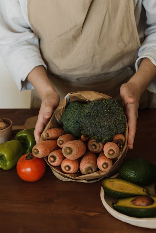 Person Holding Vegetables Wrapped in Paper