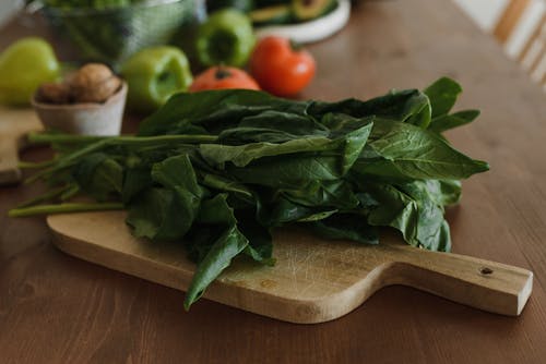 Free Close-Up Shot of Leafy Vegetables on a Wooden Chopping Board Stock Photo