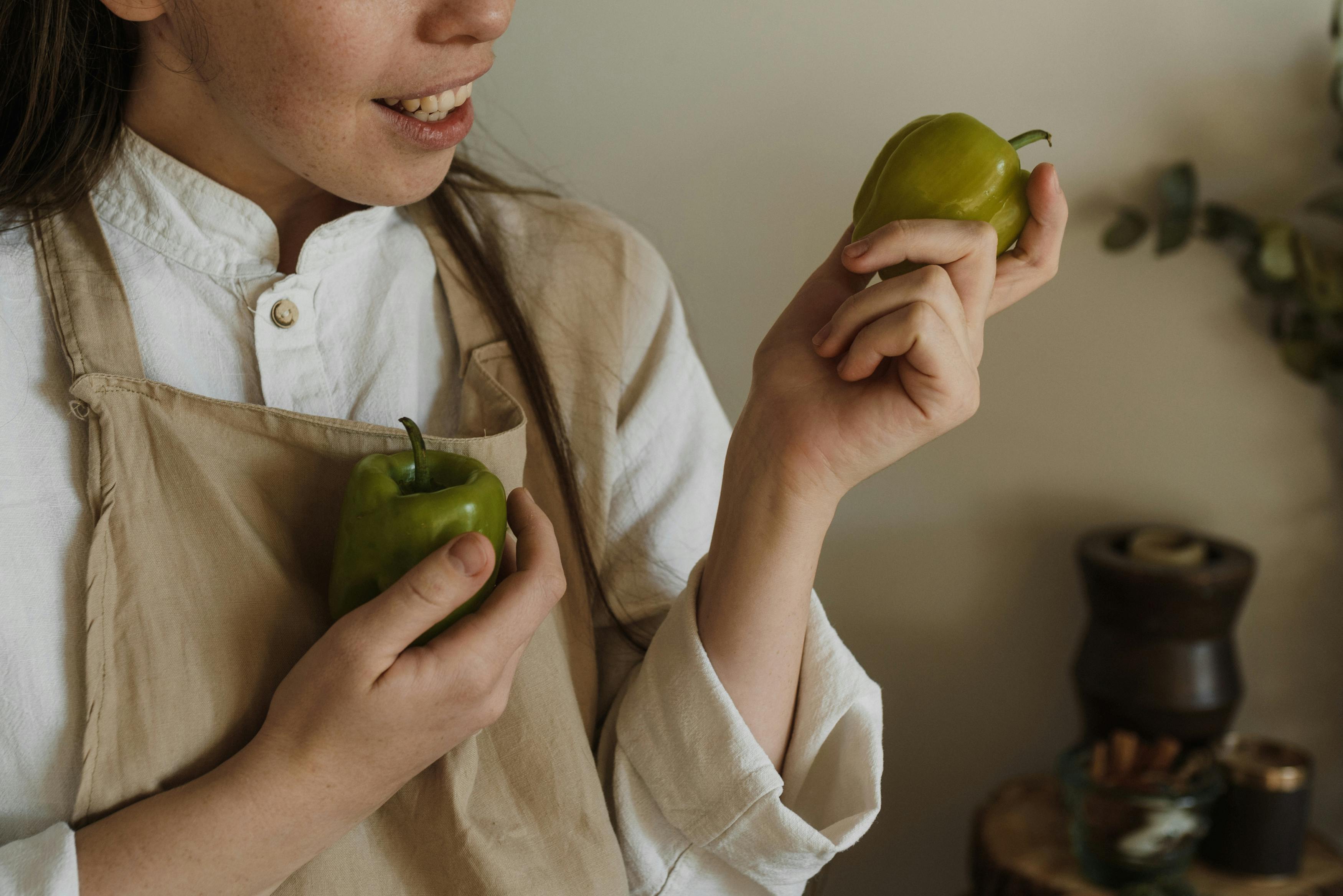 close up shot of a person holding green bell peppers