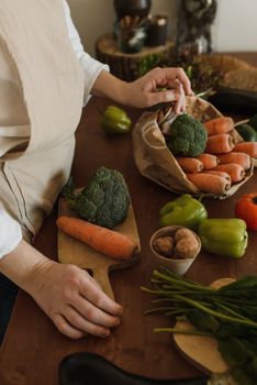 Close-up of hands arranging fresh vegetables in a cozy kitchen setting.