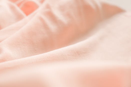 A close-up view of a soft pink pastel fabric, showcasing its delicate texture and gentle folds.