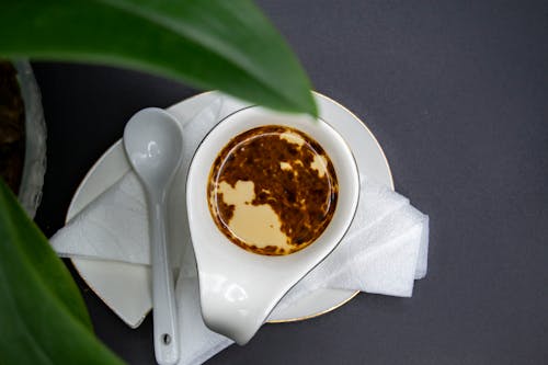 Spoon placed on plate near gravy boat with oil sauce