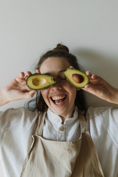 Free Happy Woman Holding Sliced Avocados Stock Photo
