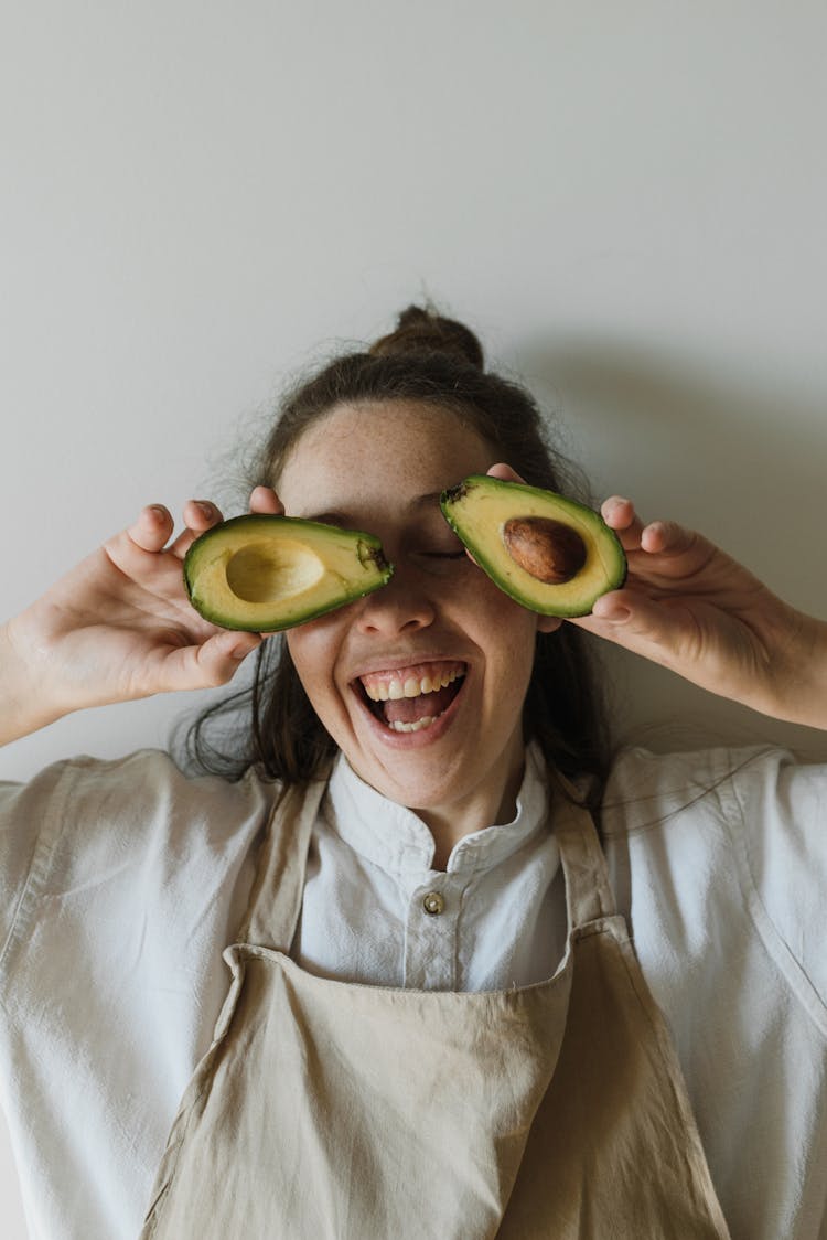 Happy Woman Holding Sliced Avocados