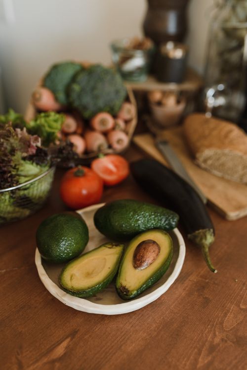 Free Rustic kitchen setup featuring fresh avocados, vegetables, and whole grain bread for a healthy meal preparation. Stock Photo