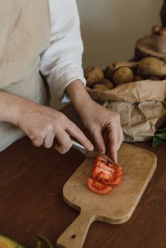 Close-up of hands slicing tomatoes on a wooden chopping board, emphasizing fresh, healthy cooking.