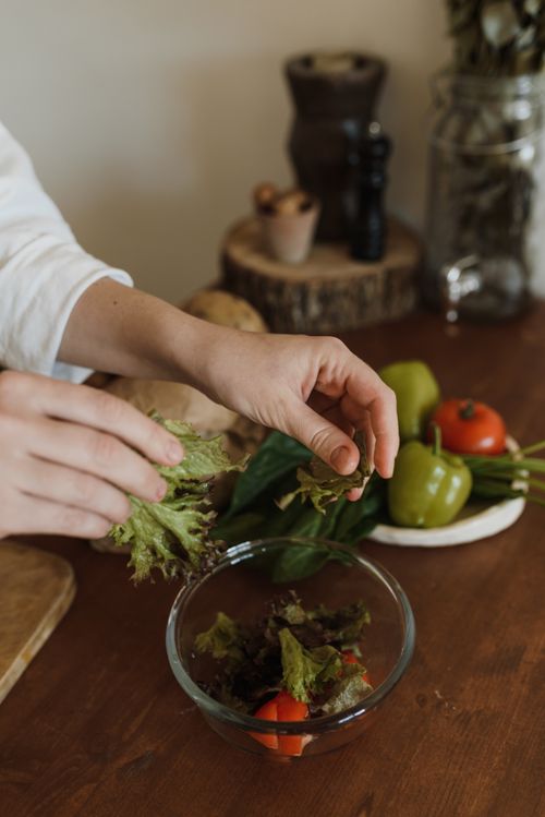 Free Hands preparing a fresh salad with organic vegetables in a kitchen setting. Stock Photo