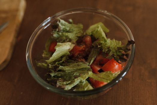 A fresh and healthy salad featuring crisp lettuce and juicy tomatoes in a glass bowl.