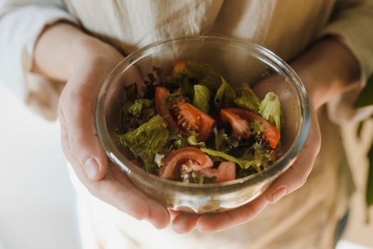 Close-up of fresh vegetable salad with tomatoes and lettuce in a glass bowl.