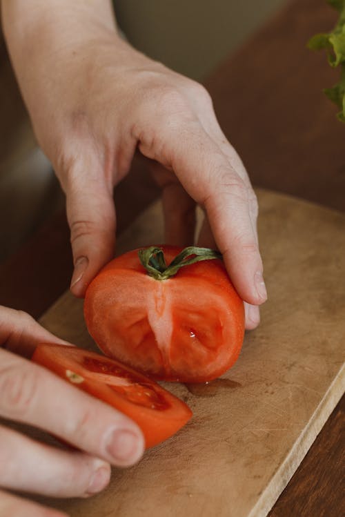 Close Up Shot of a Person Holding Sliced Tomato