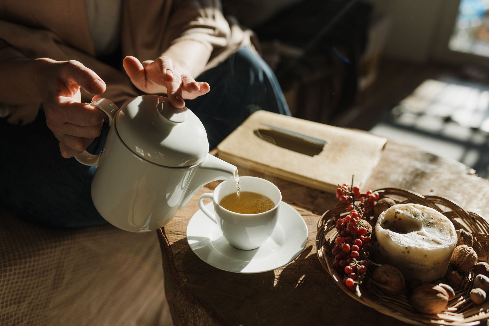 Pouring tea into a cup on a cozy afternoon with warm sunlight filtering indoors.