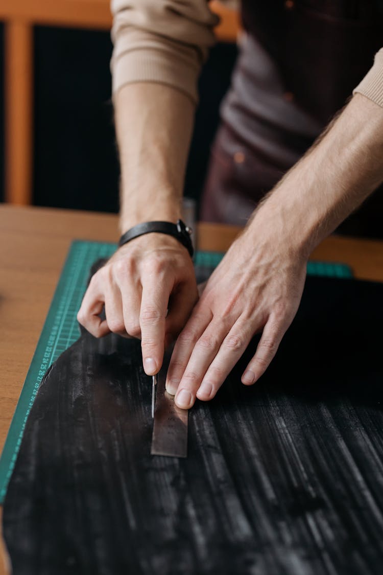 Close-up Of Man Measuring And Cutting A Black Fabric 