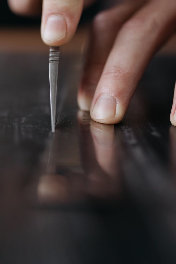 Close-up Of Person Using Cutter On Steel Surface