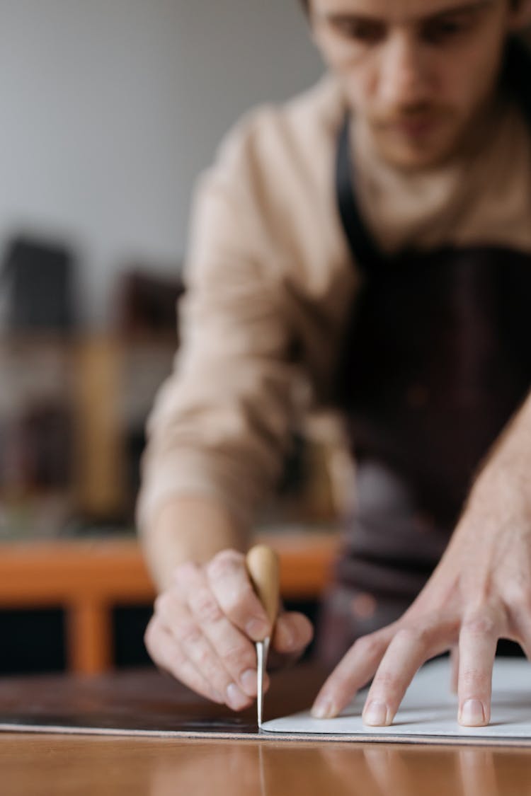 A Man Marking A Black Material With A Chisel