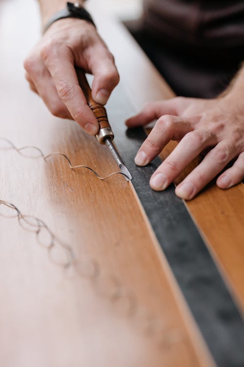 A Person Scraping a Wood with a Chisel