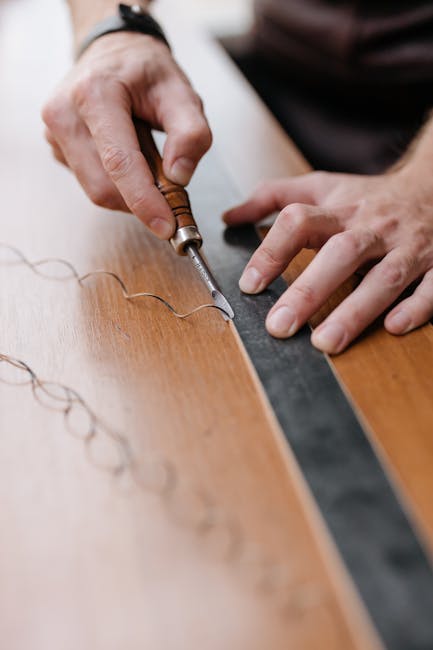 Focused shot on hands using a chisel and ruler to intricately engrave designs on a wooden surface.