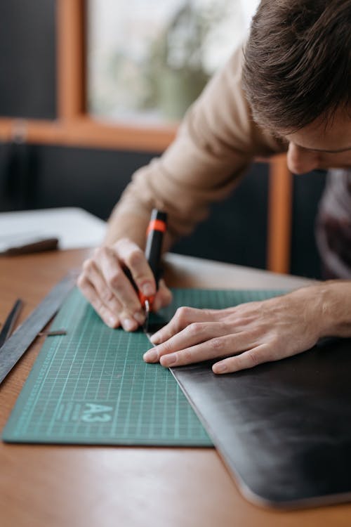 Free A Person Cutting a Black Material Stock Photo