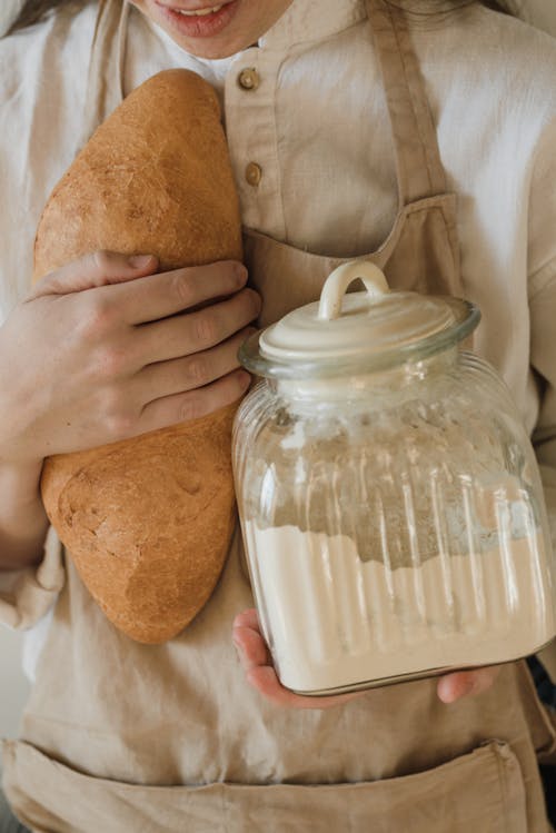 Free Close Up Photo of a Person Holding Bread and a Glass Jar Stock Photo