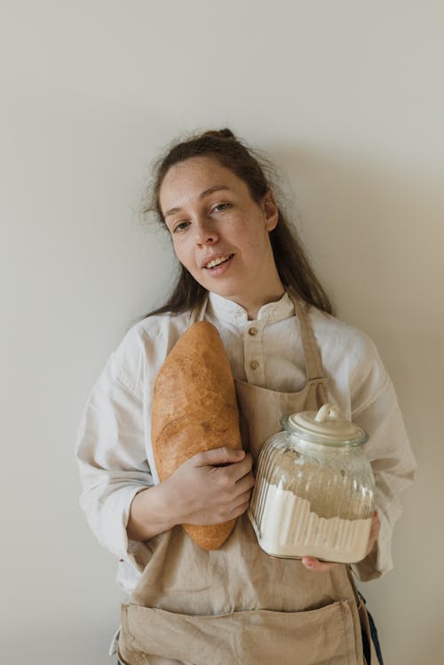Free Person Wearing Apron Holding Bread and a Glass Jar Stock Photo