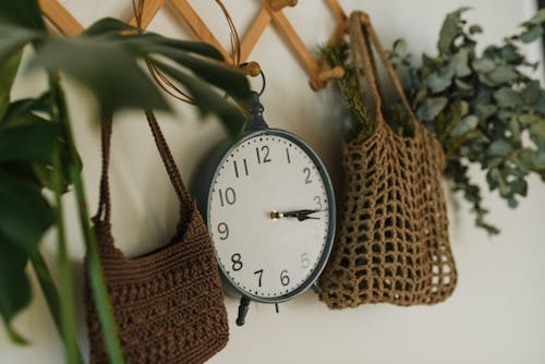 An Analogue Clock Hanging Between Crocheted Bags