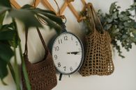 An Analogue Clock Hanging Between Crocheted Bags