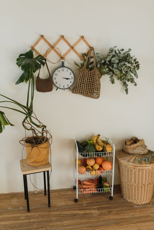 Free Assorted Fruits and vegetables in a Rack Under Bags and Clock Hanging on the Wall Stock Photo