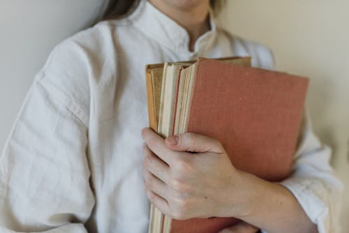 A Person in White Shirt Holding Brown Book