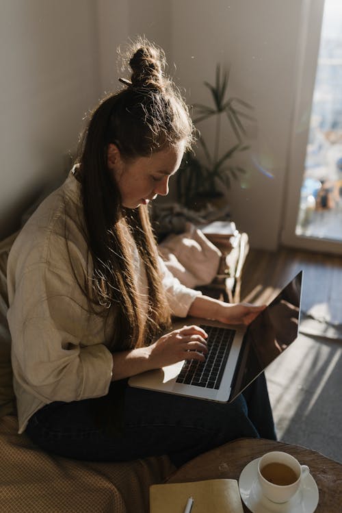 Free A Woman Sitting in the Living Room Using a Laptop Stock Photo