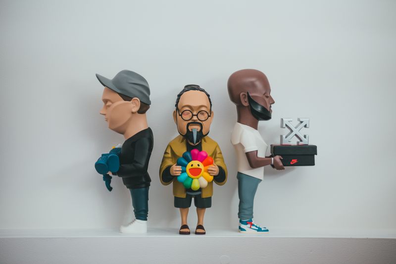 Miniature figures of people holding different objects representing art toy character storytelling and BaiChaoHui Zombie Party narrative