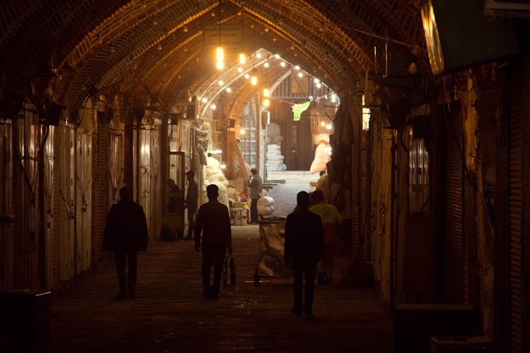 People Walking On A Hallway With Lights Hanging From Ceiling