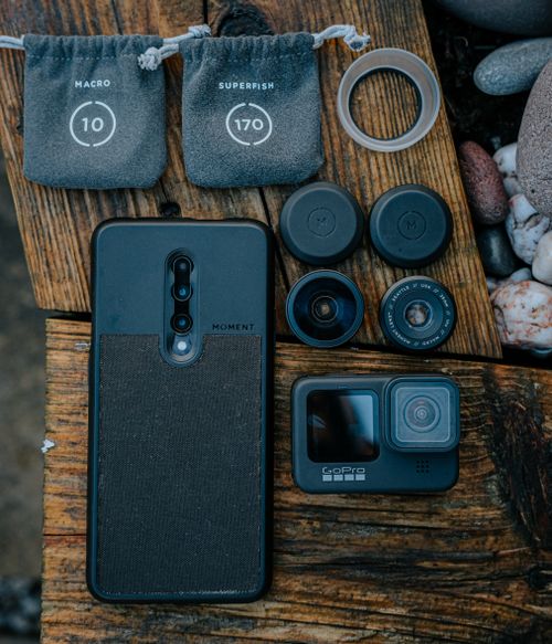 Free A flatlay showcasing mobile photography gear including lenses, a phone, and a camera on a wooden background. Stock Photo