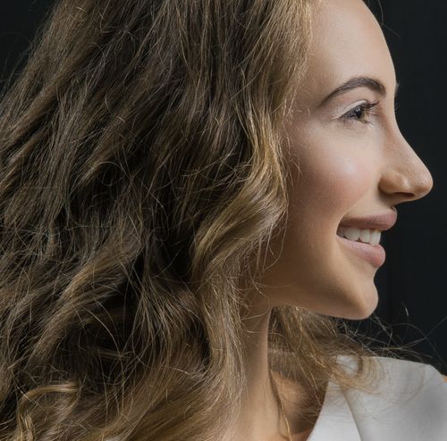 Free Close-up of a smiling woman with curly hair in profile view highlighting natural beauty. Stock Photo