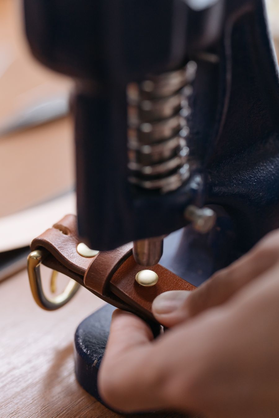 Installing metal eyelets on leather using press machine at Eyelets Hub factory, Lahore