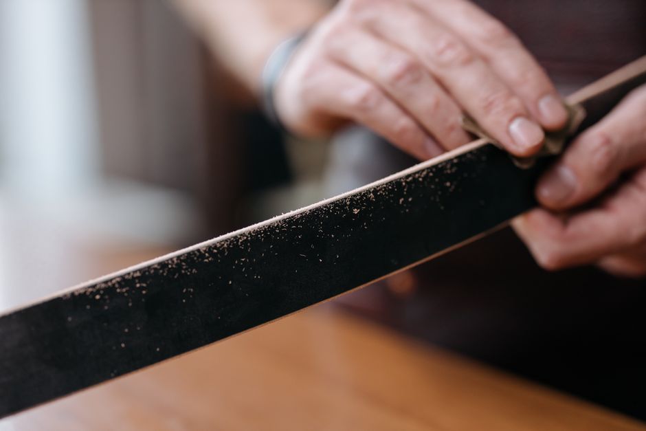 Handcrafted leather belts being finished in a workshop Handcrafted leather belts being finished in a workshop