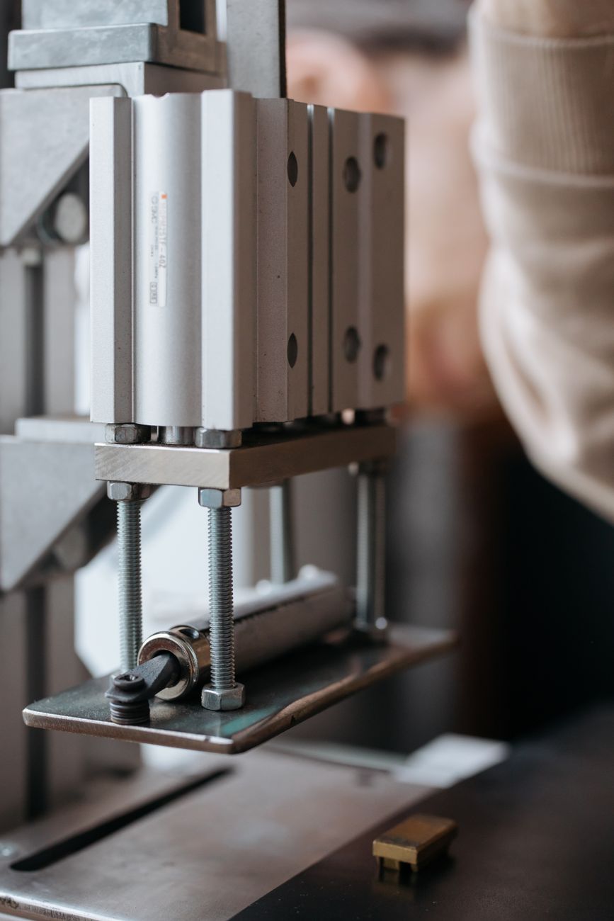 Detailed view of a stainless steel machine with screws and nuts, highlighting industrial machinery.