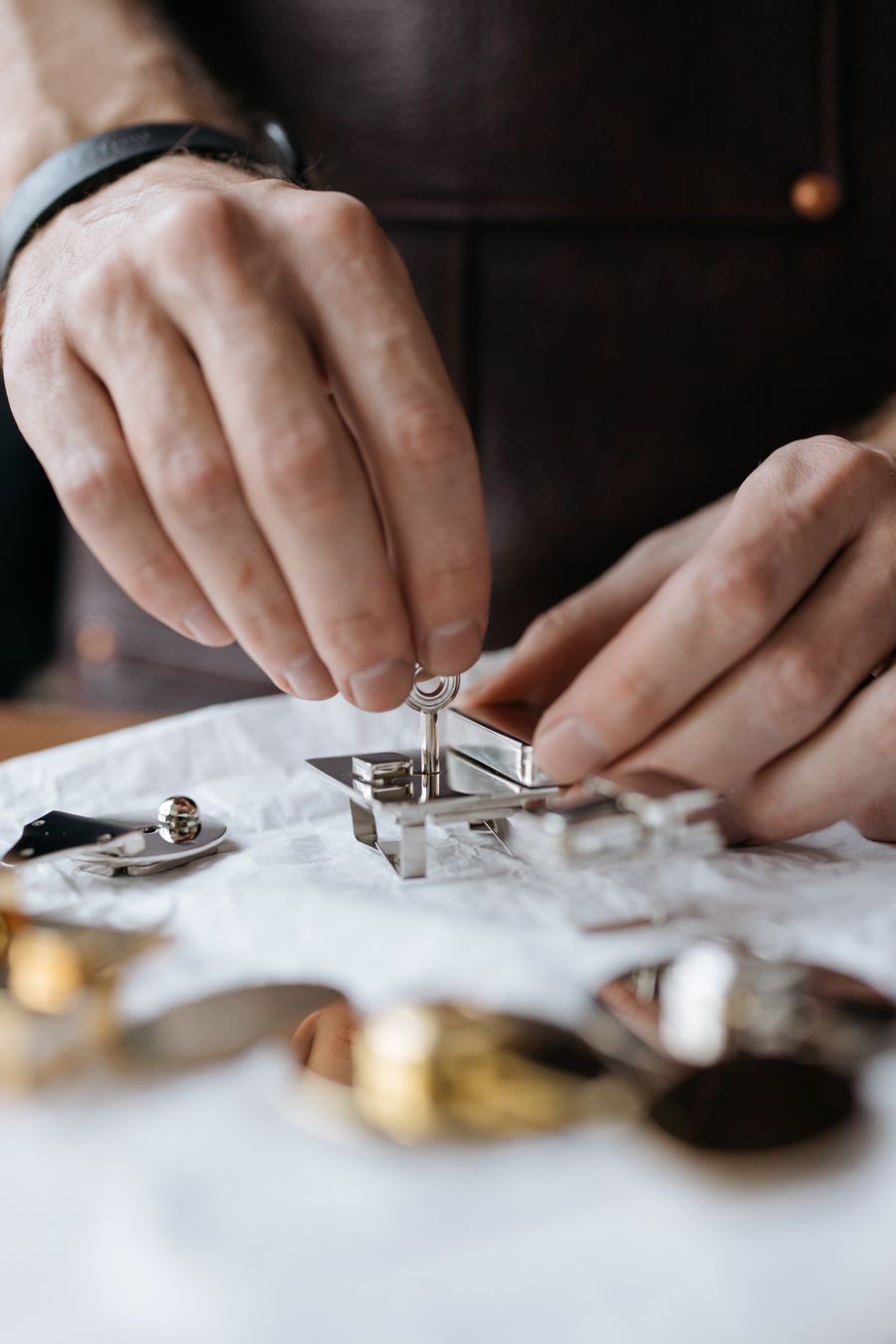 A locksmith's hands reassembling a small polished lock on a workbench