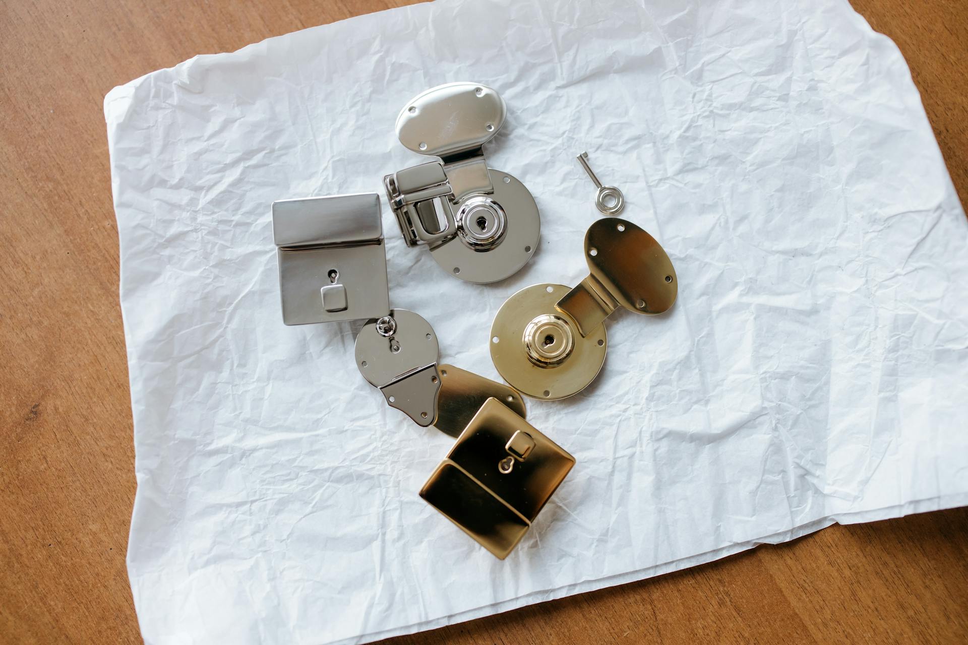 A collection of shiny metallic locks and a key displayed on crumpled paper.