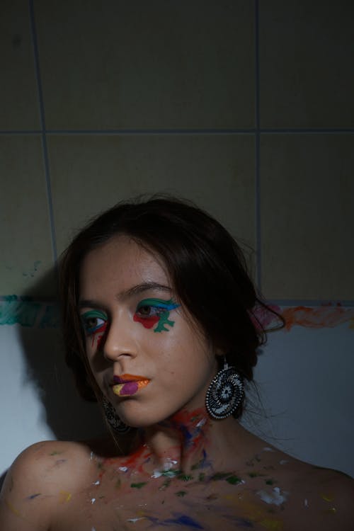 Close-Up Shot of a Woman with Face Paint Lying on a Bathtub