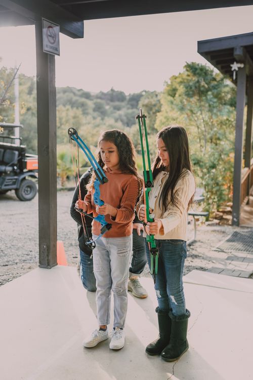 Free Two girls practicing archery outdoors with recurve bows on a sunny day. Stock Photo