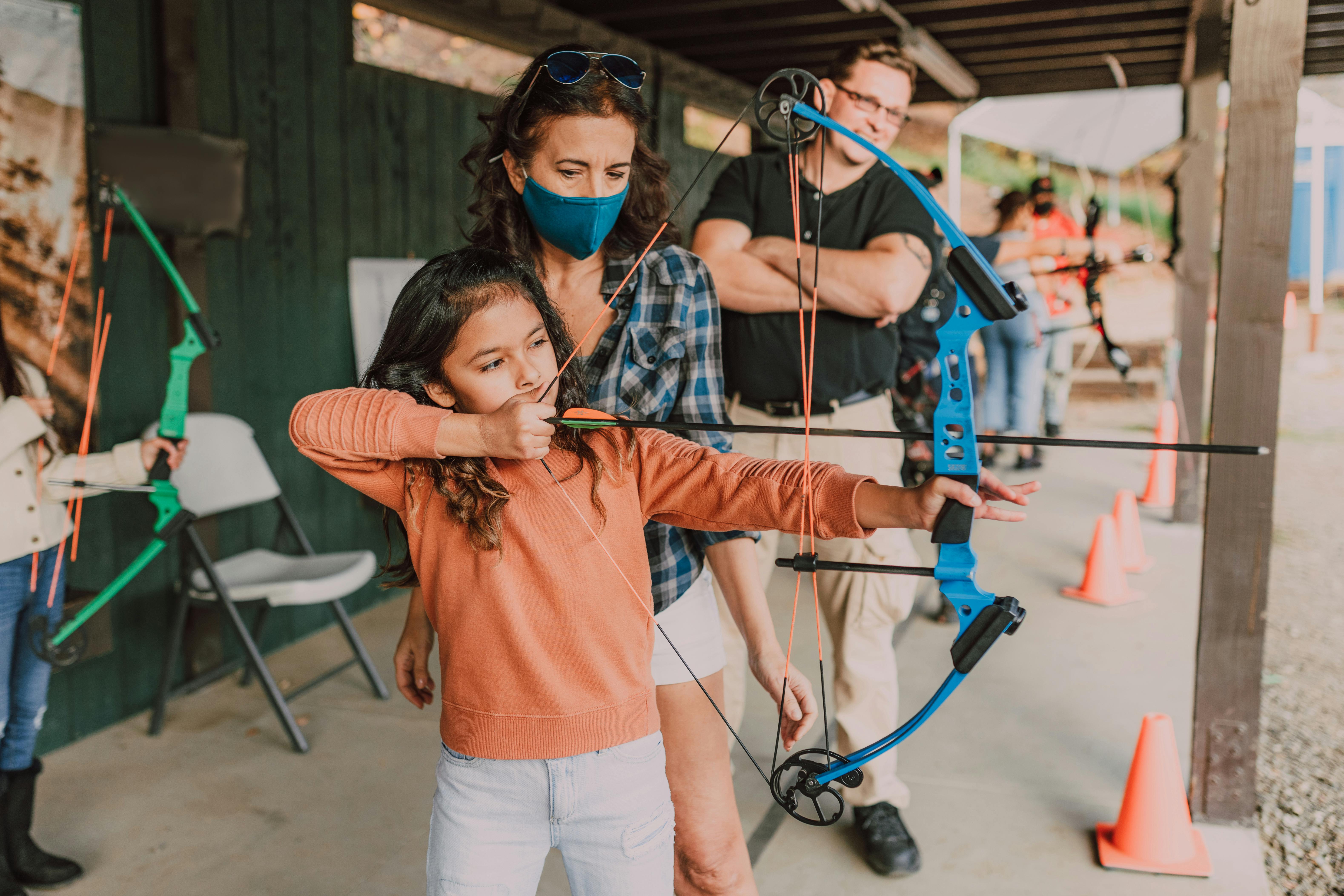 woman in orange shirt holding bow and arrow