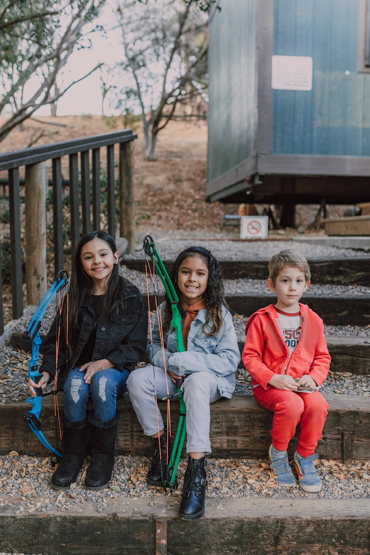 Children Holding An Archery Bow While Sitting