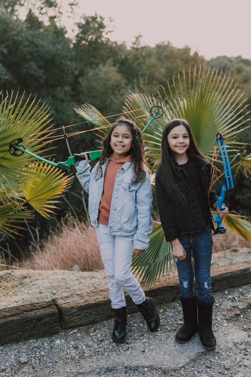 Free Two young girls enjoying archery practice in a natural setting. Stock Photo