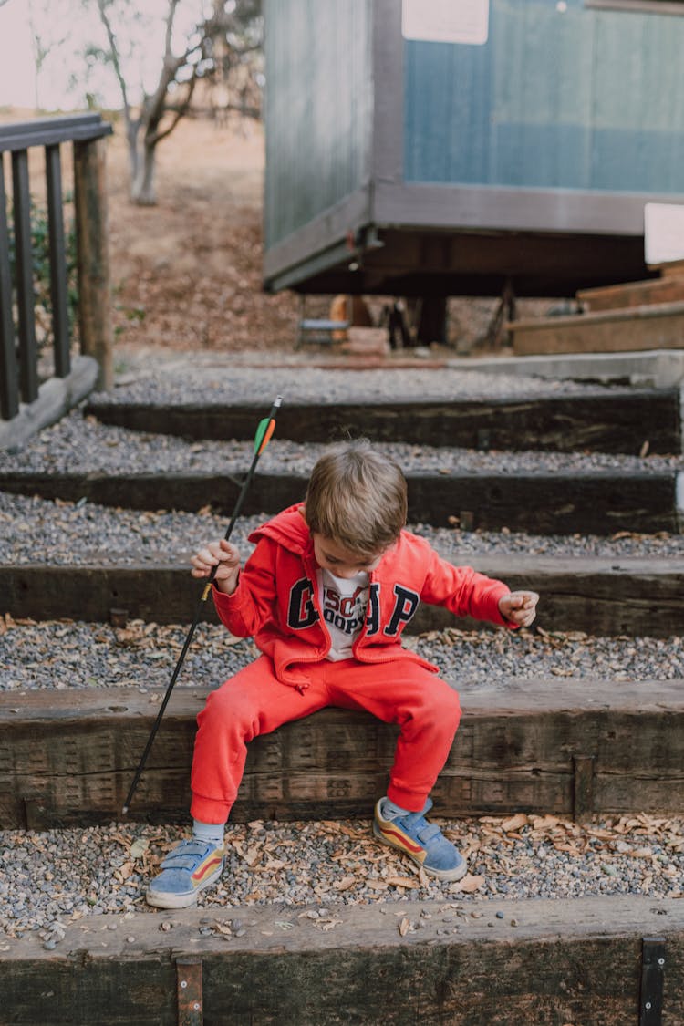 Photo Of Kid In Red Jacket Sitting On Stairway