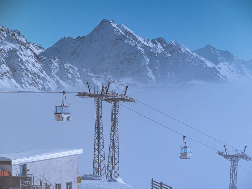 Cable cars transporting skiers with snowy mountains in a serene winter landscape.