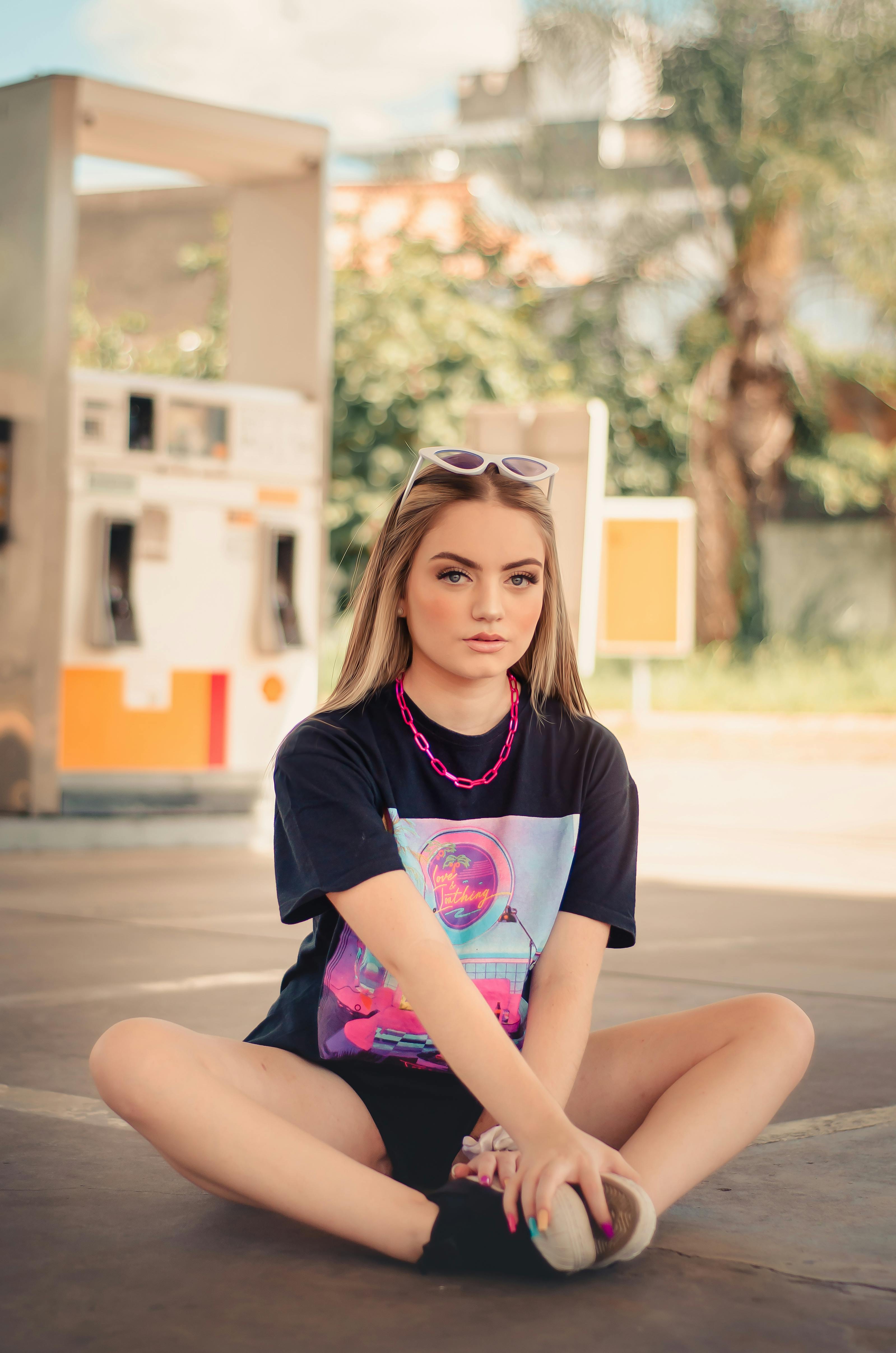 portrait of a blond girl sitting on pavement on at petrol station