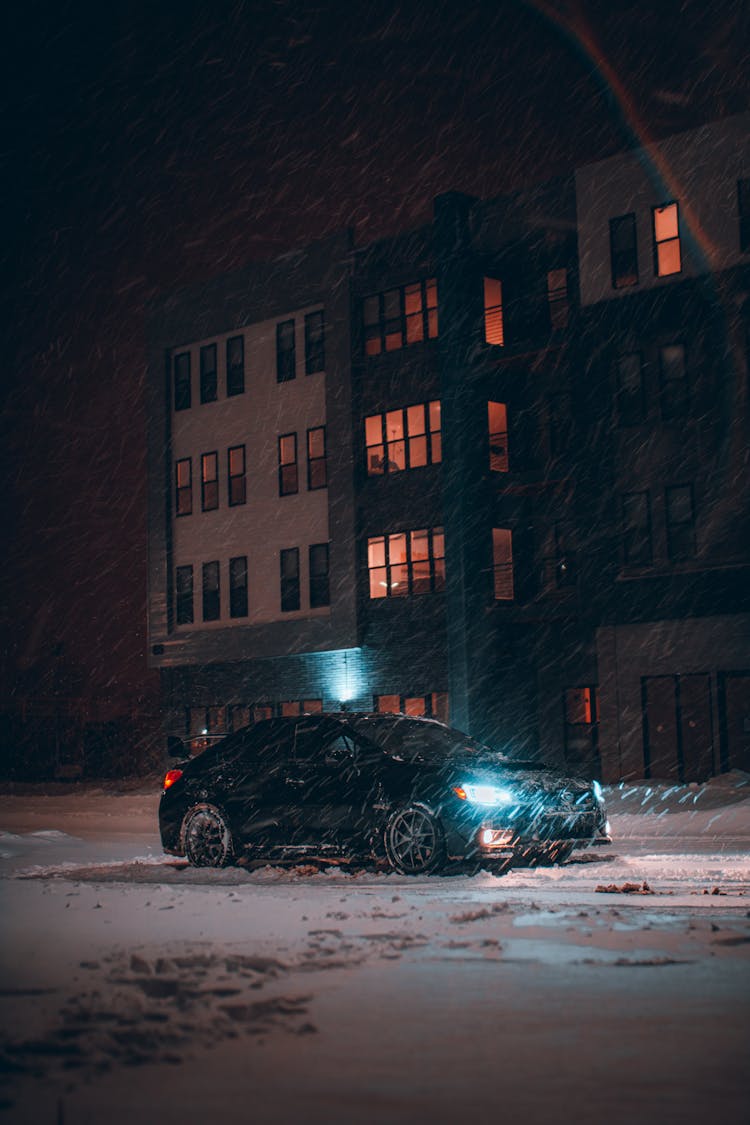 Car Parked In Empty Parking Lot During Snowstorm