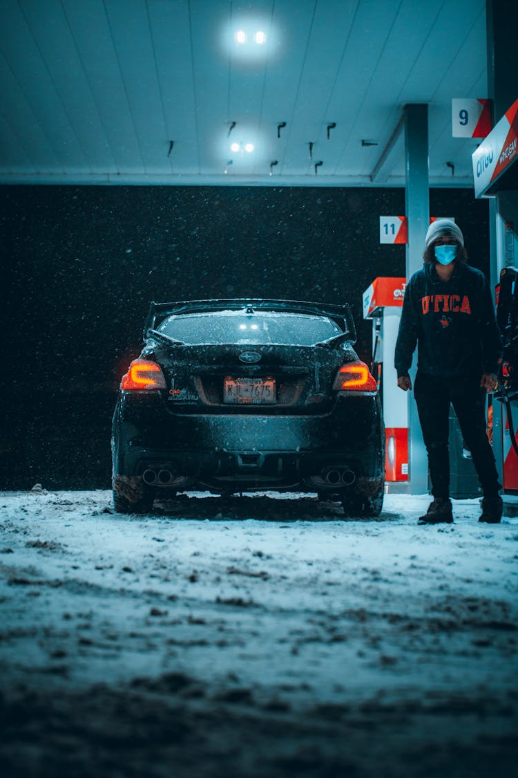 Man In Safety Mask On A Gas Station In Winter At Night 