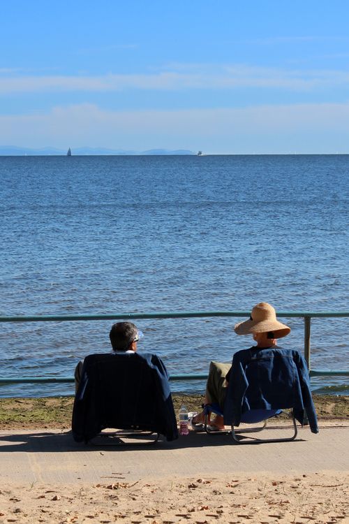 Free A couple seated by the ocean enjoying a peaceful seaside view in summer. Stock Photo