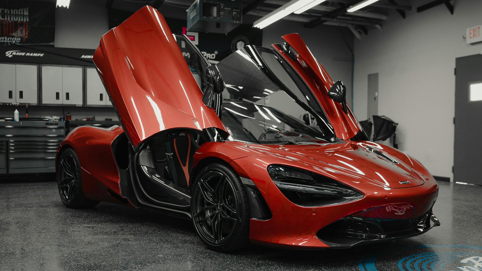 Luxury red sports car with open butterfly doors in modern garage setting.