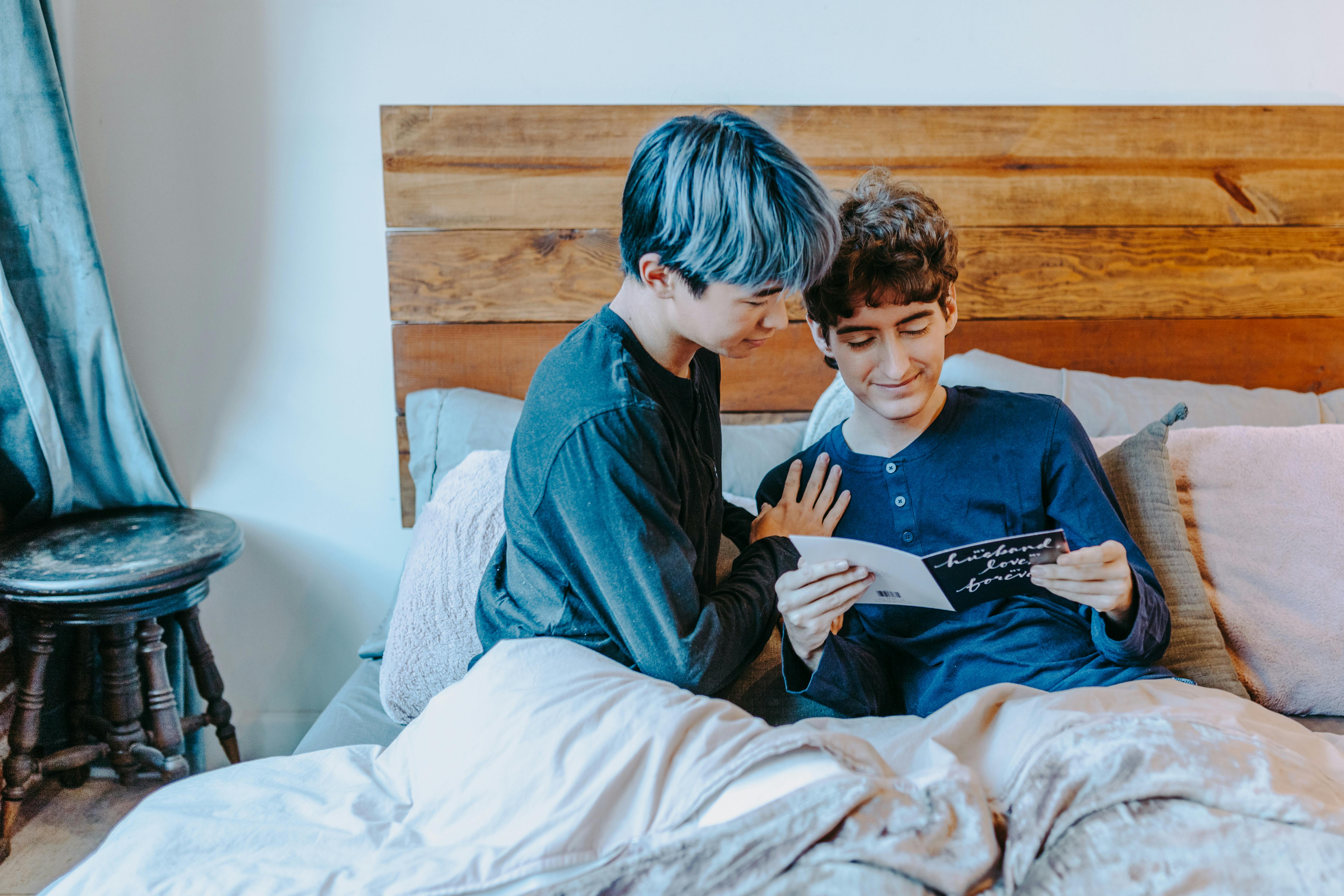 boy in blue sweater sitting on bed